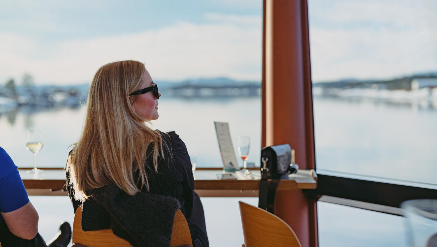 Girl sitting inside the boat, looking at the view through the panoramic window.