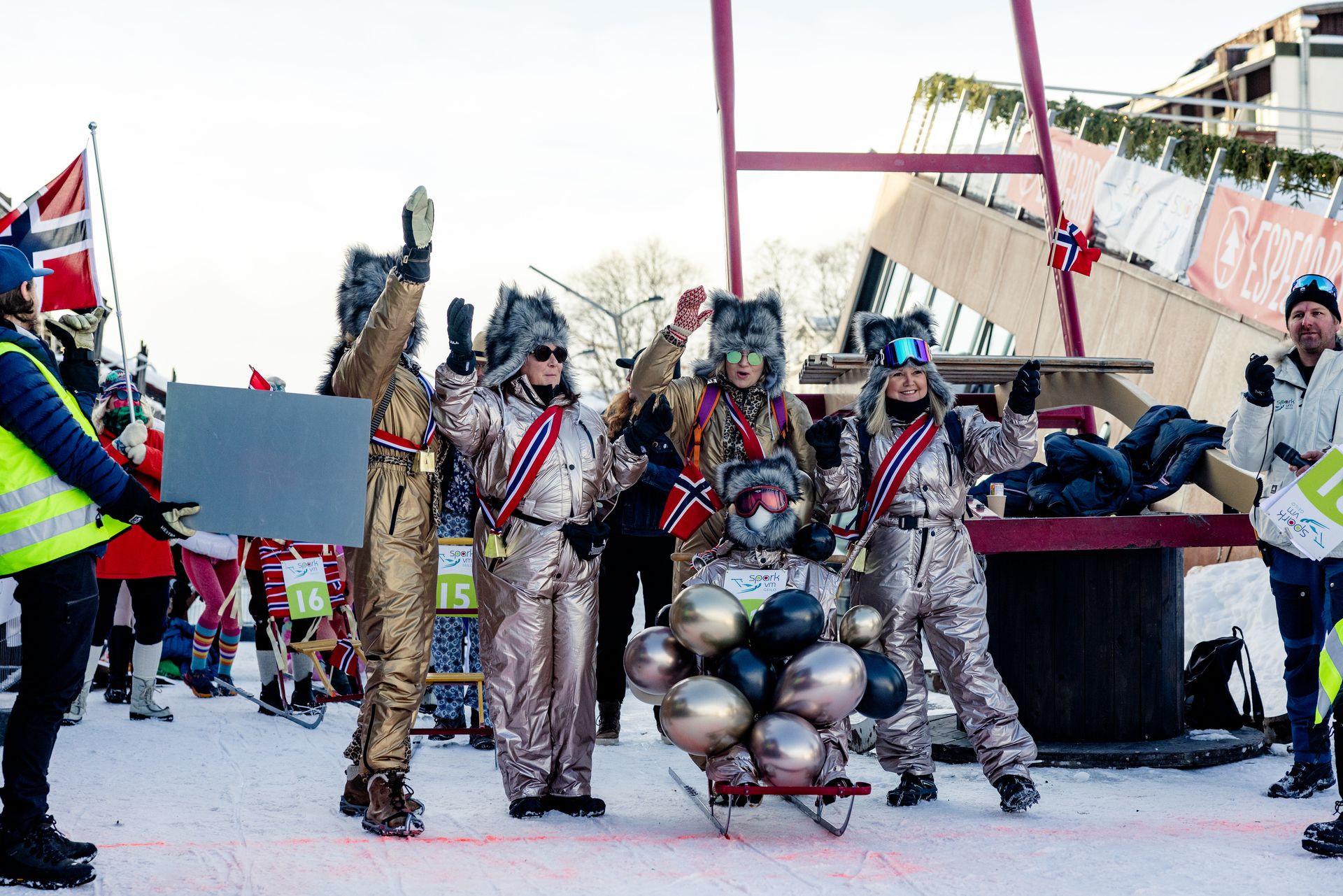 A large group of people participating in the Kicksled World Championship is sliding down the snow-