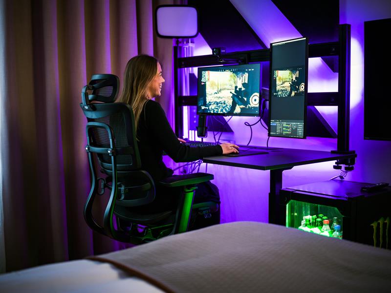 Female gamer in a chair in front of several screens gaming