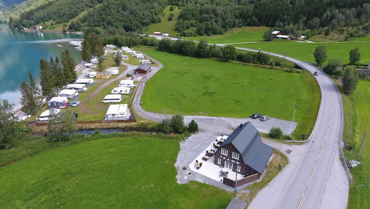 Droneutsikt over Grande Camping ved Oppstrynsvatnet i Oppstryn, omgitt av fjell og den blågrøne fargen frå brevatnet.