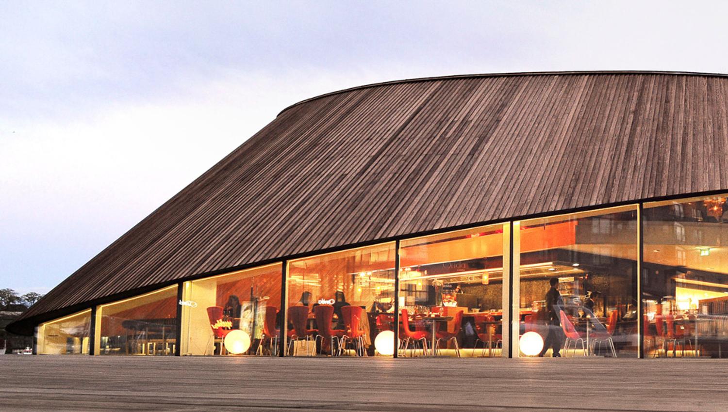 Eksteriørbilde av brun restaurant med store vinduer.
