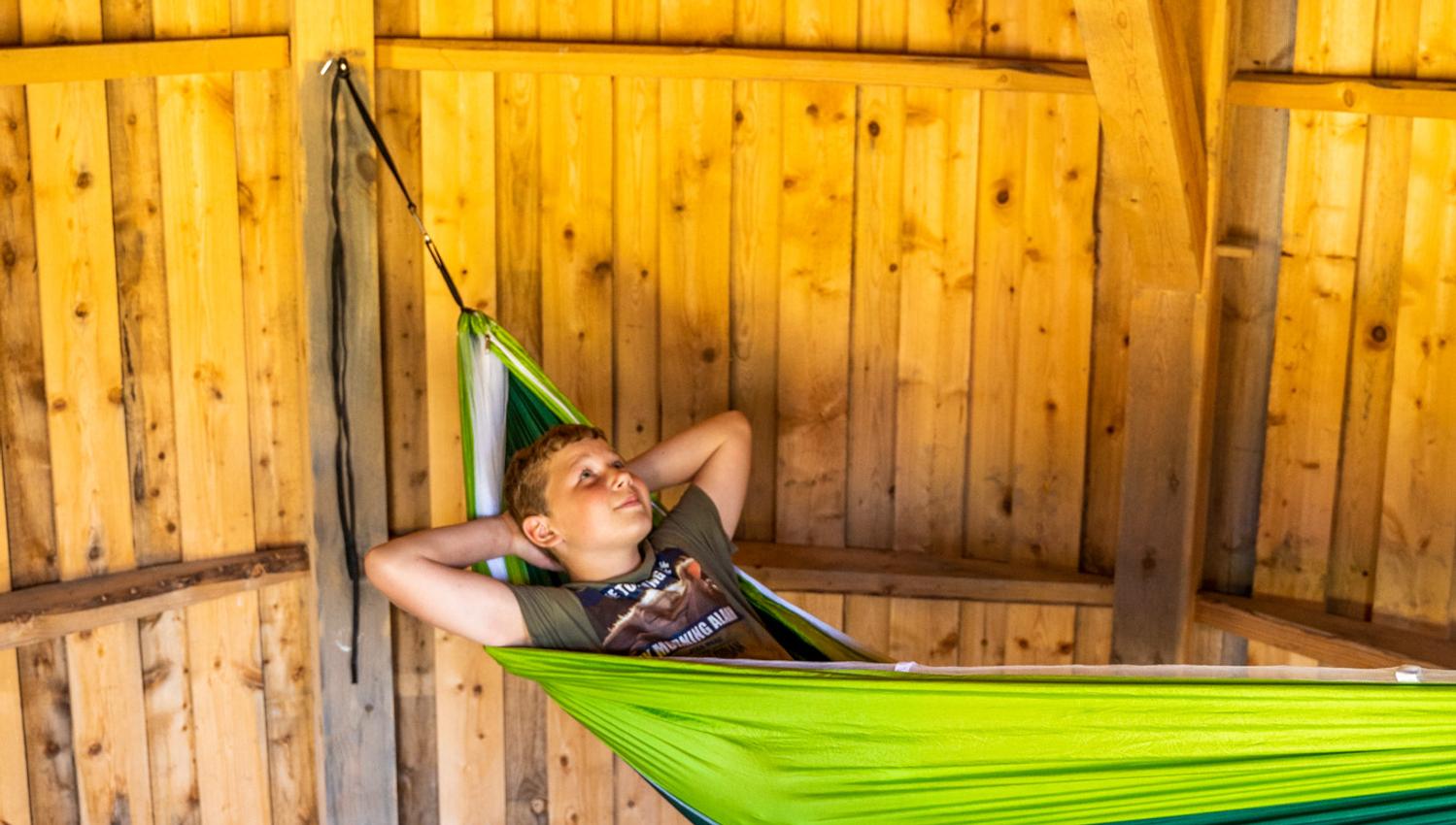 Gutt i hengekøye inni en hytte