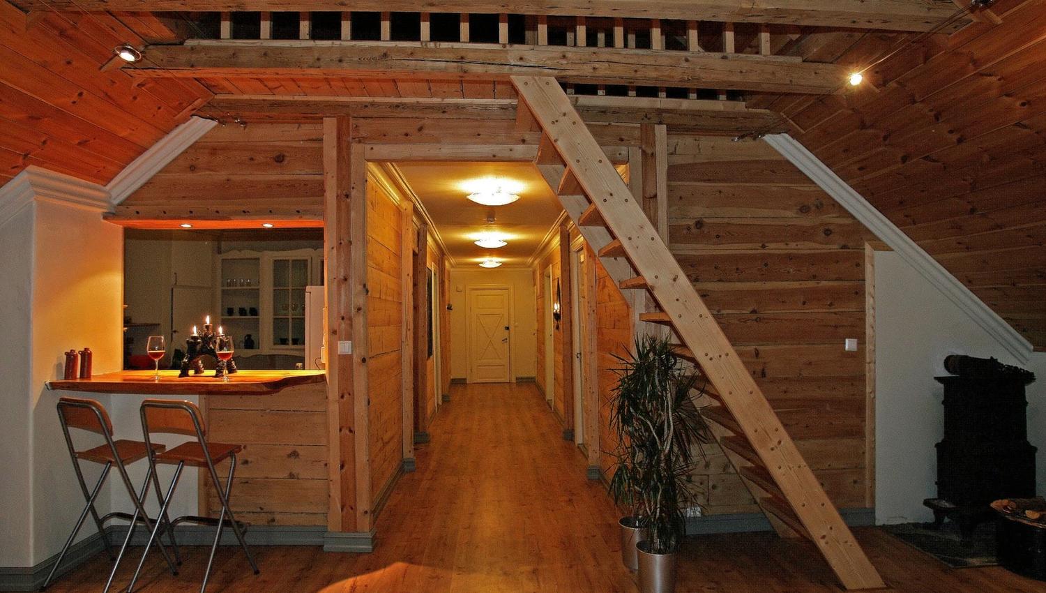 Lys og triveleg fellesstove på Vikinghaug Apartments med treinteriør, barløysing og open trapp, ideell for sosiale kveldar.
