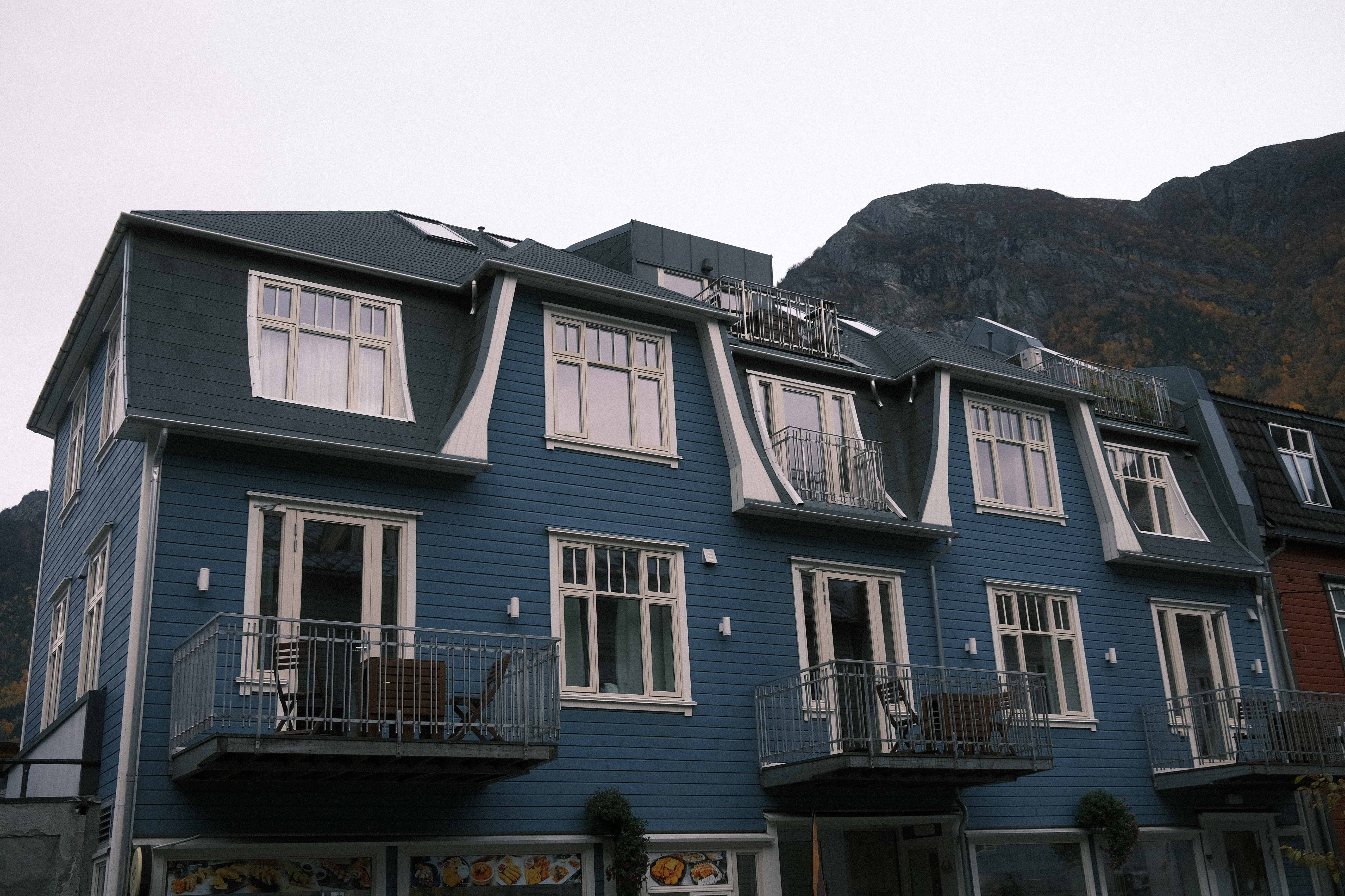 Den blå fasaden til Blue House Odda med fjellandskap i bakgrunnen, sentralt plassert i Odda.