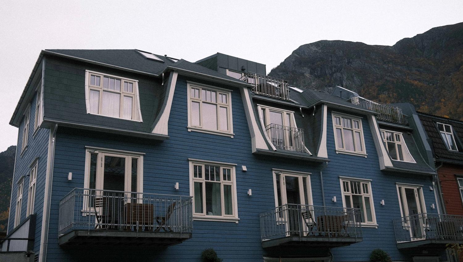 Den blå fasaden til Blue House Odda med fjellandskap i bakgrunnen, sentralt plassert i Odda.