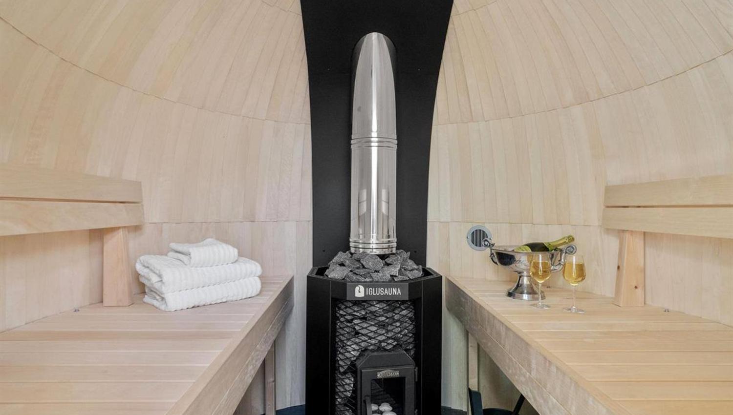 Interior of a barrel sauna with wooden benches and a central stove.