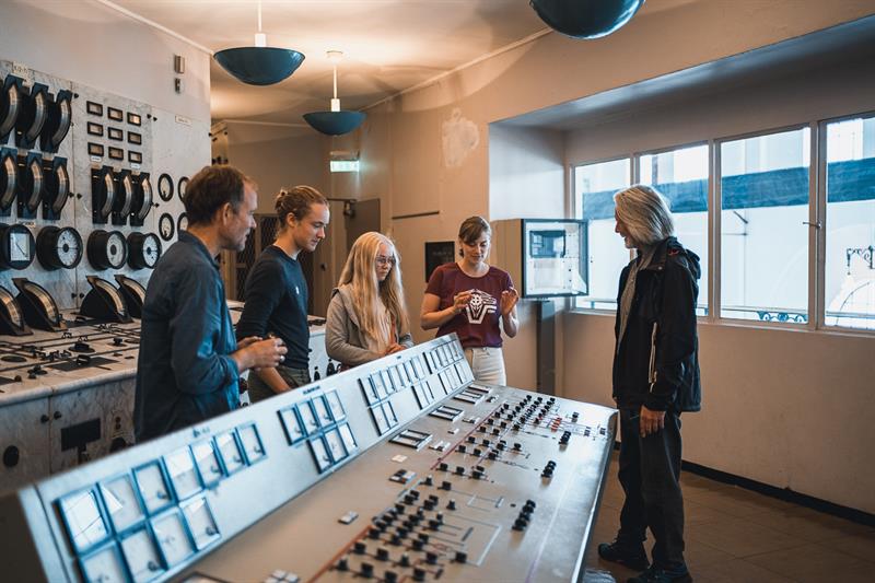 Gruppe besøkande inne i kontrollrommet på Kraftmuseet, der dei lærer om norsk energihistorie.