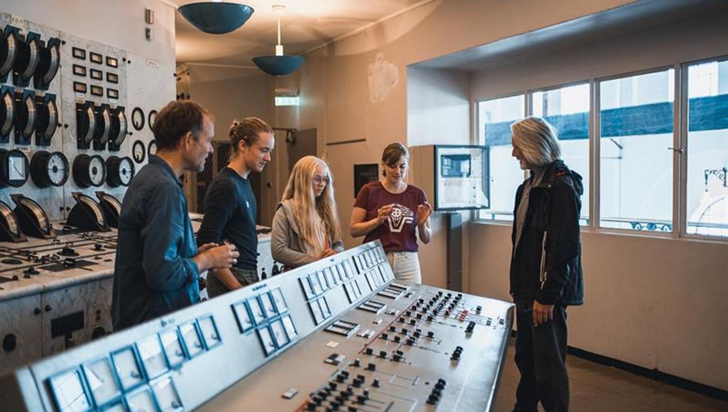 Gruppe besøkande inne i kontrollrommet på Kraftmuseet, der dei lærer om norsk energihistorie.