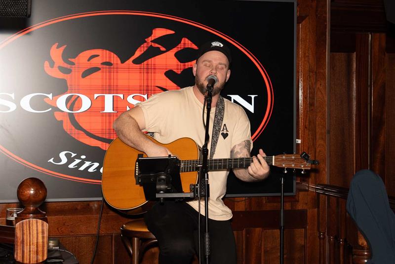 Mann som opptrer med gitar på scenen