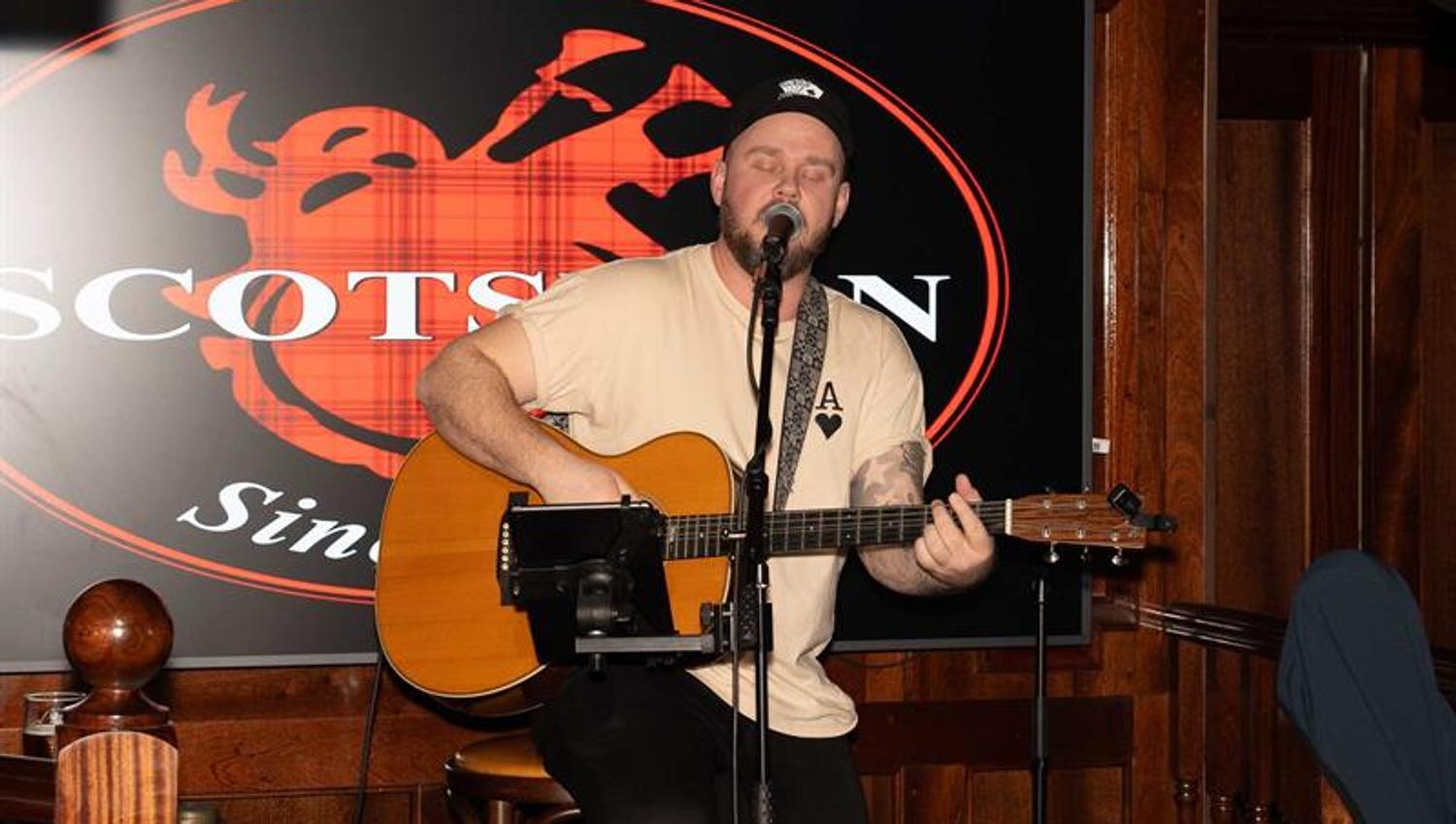 Mann som opptrer med gitar på scenen