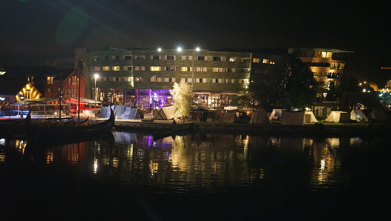 The Viking ship Saga Oseberg on the pier in Tønsberg in the evening while the town lights up
