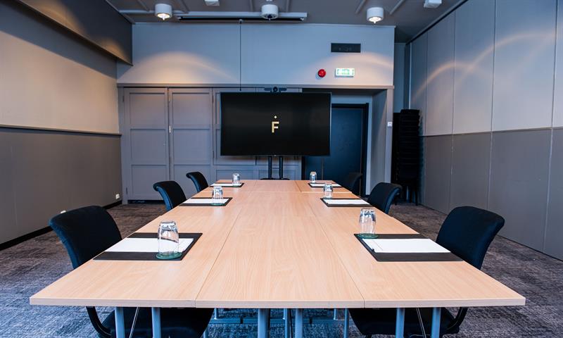 Et møterom med stoler rundt et langt bord og en storskjerm i bakgrunnen