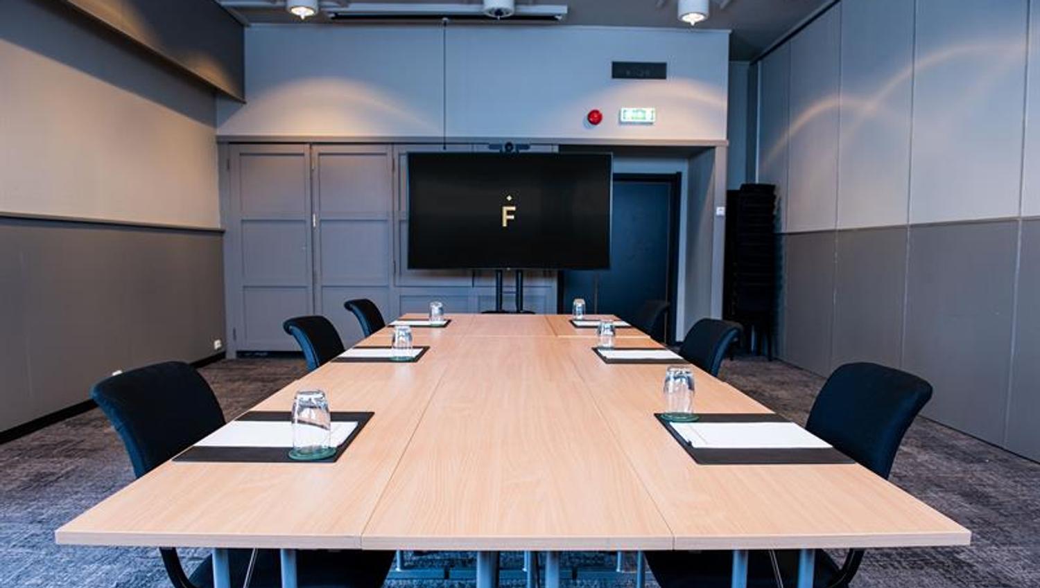 Et møterom med stoler rundt et langt bord og en storskjerm i bakgrunnen