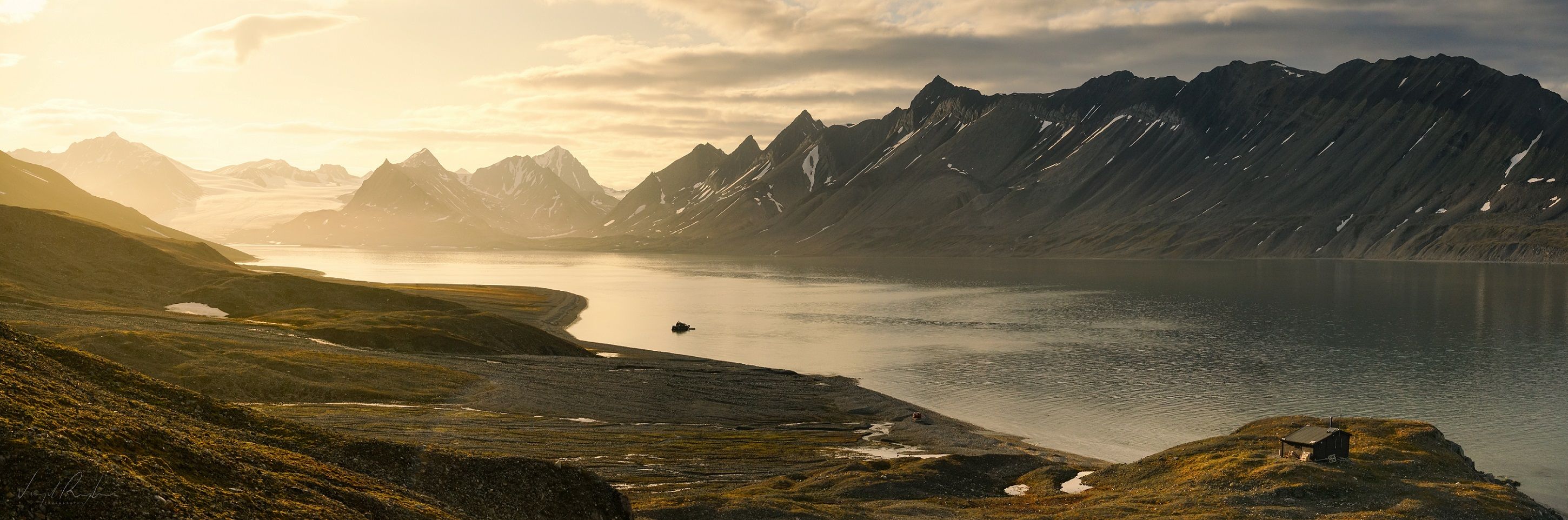 A boat floating in a calm fjord with a mountainous landscape in the background