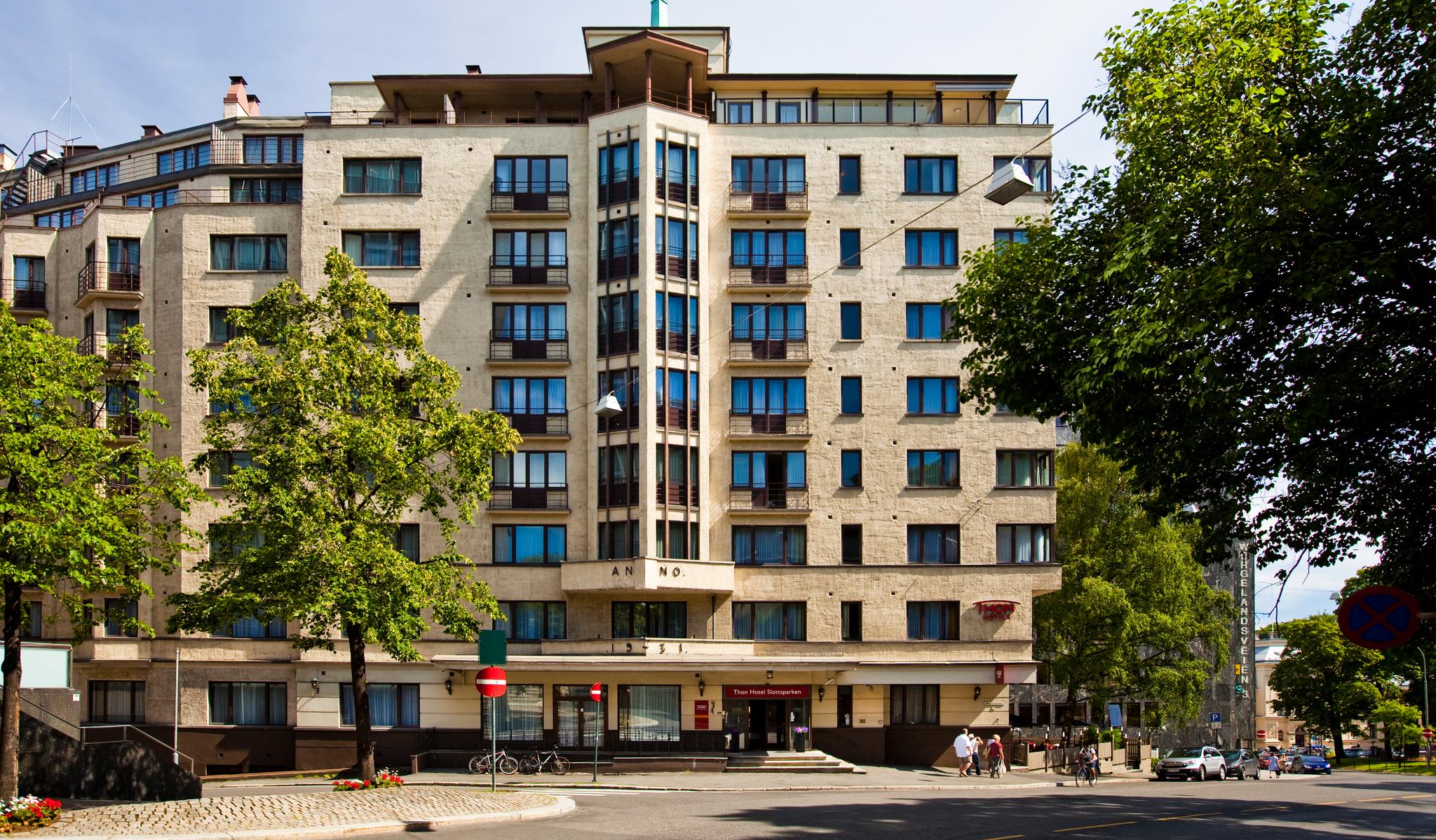 Thon Hotel Slottsparken, lys fasade med 9 etasjer. Grønne trær, blå himmel. Foto.