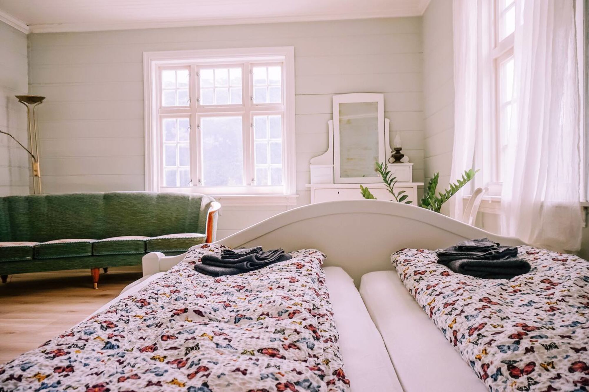 Romslig soverom med sofa og store vindu.