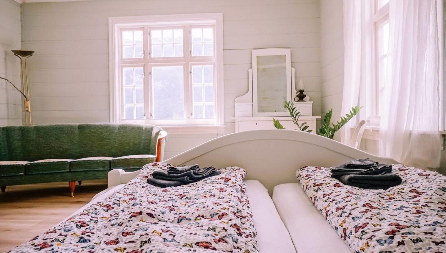 Romslig soverom med sofa og store vindu.