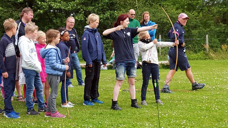 Children and adults shoot with a bow and arrow