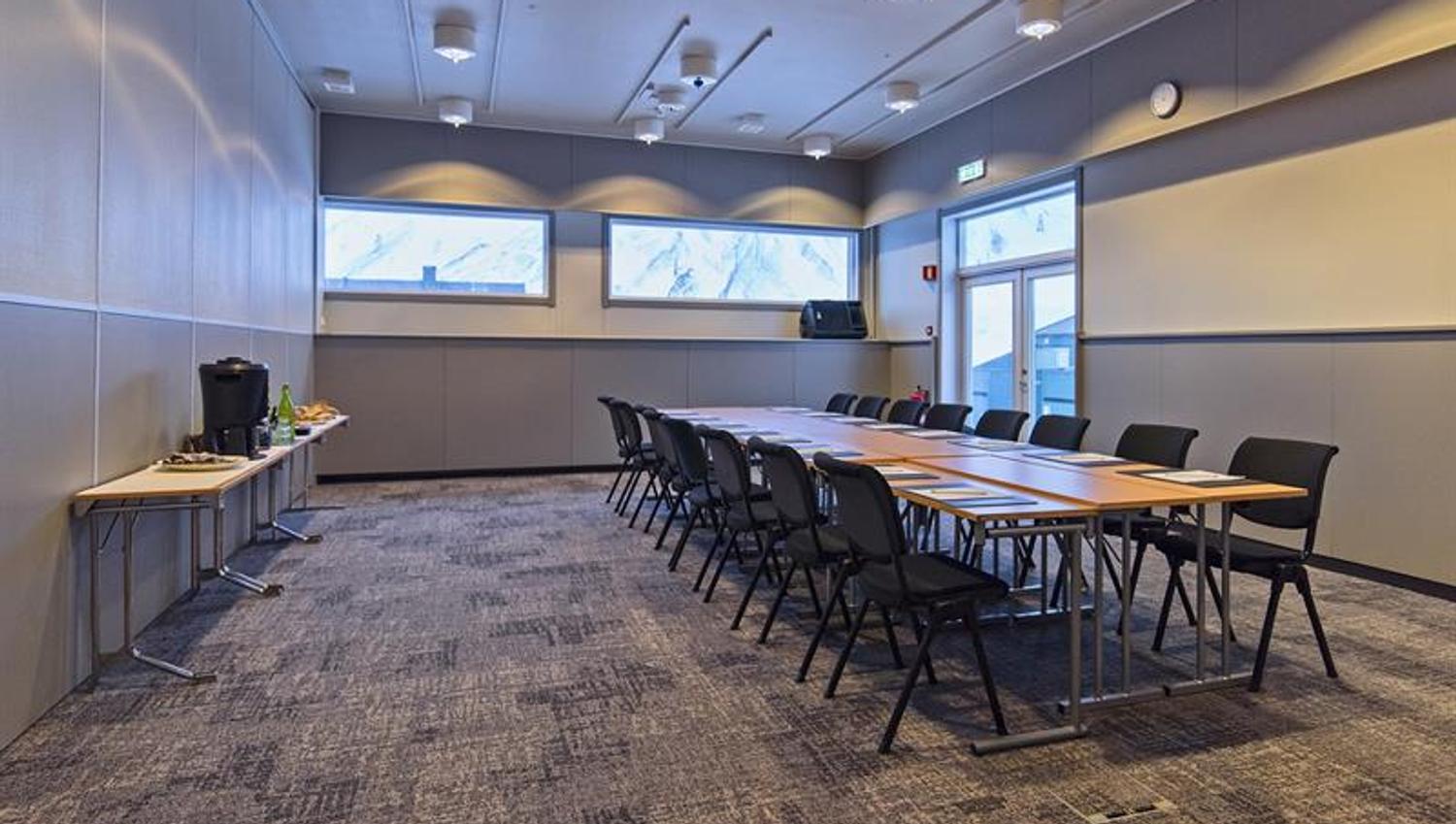 Et konferanserom med langbord, stoler og servering