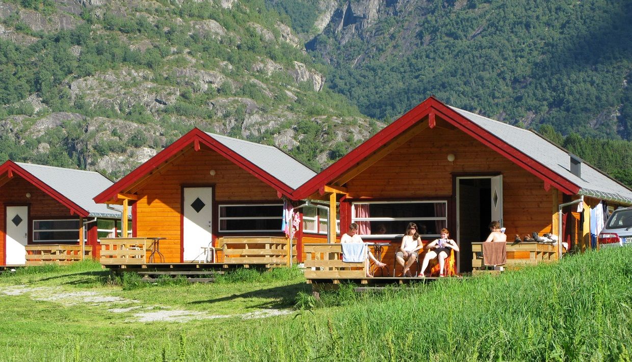 Tre av hyttene på campingplassen, med folk som slapper av på en av terrassene.