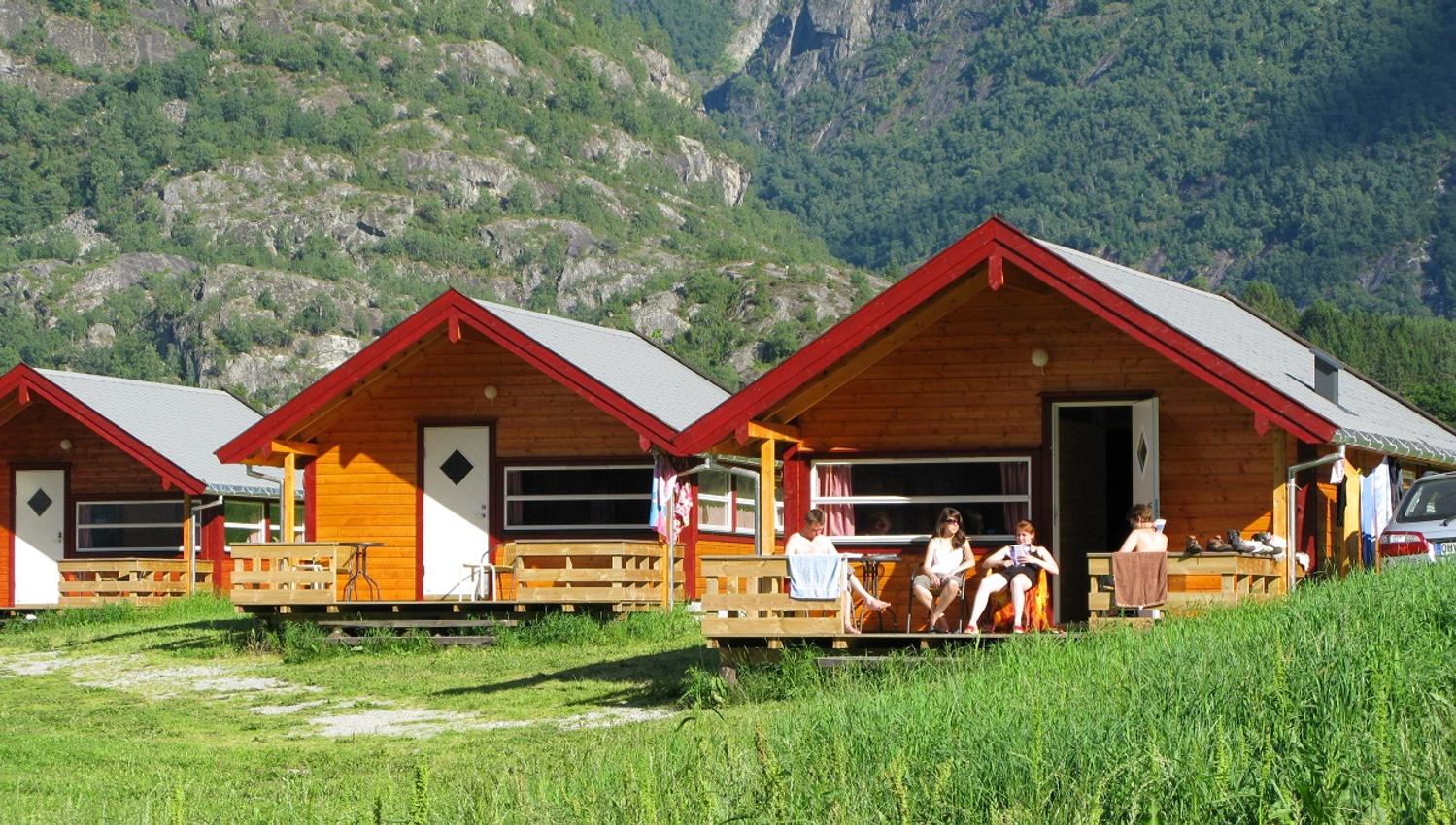 Tre av hyttene på campingplassen, med folk som slapper av på en av terrassene.