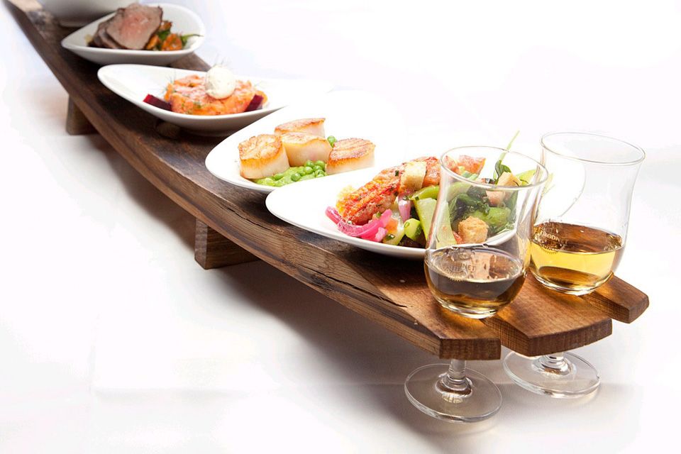 Detaljbilde av diverse småretter på et brett og to vinglass.