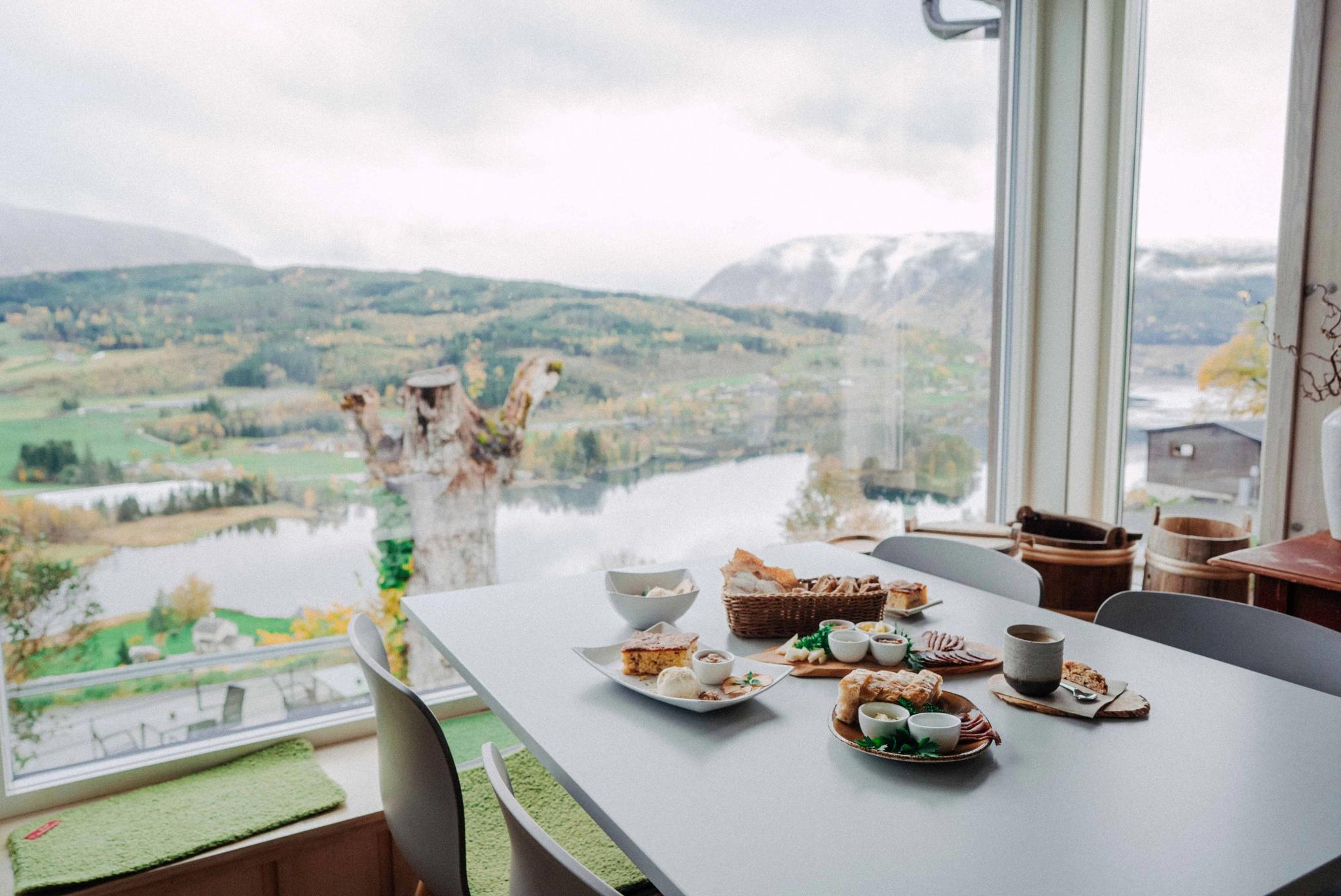 A table filled with local food from Hardanger, overlooking a panoramic fjord landscape.