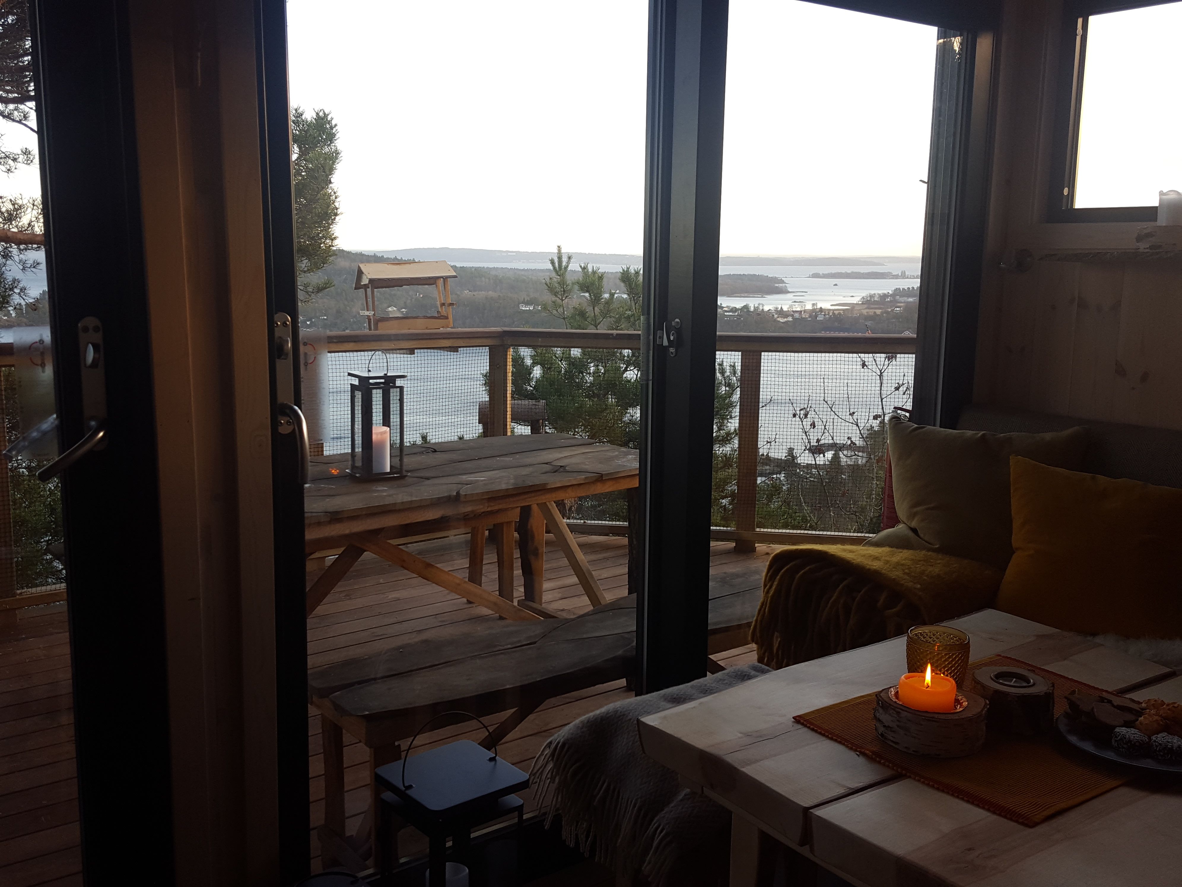 Stue på kveldstid, med utsikt ut over naturen og vannet