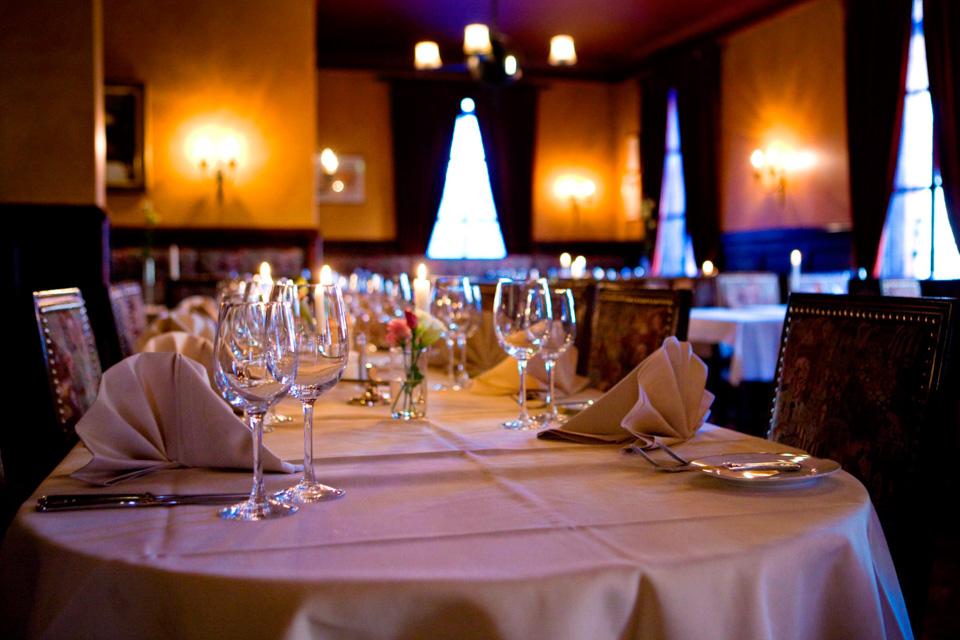 A long table with a white cloth set for dining, with wine glasses.
