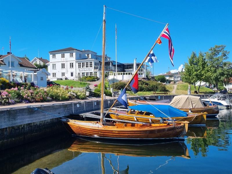 Wooden boats on the water in front of the Badehotellet, blue sky