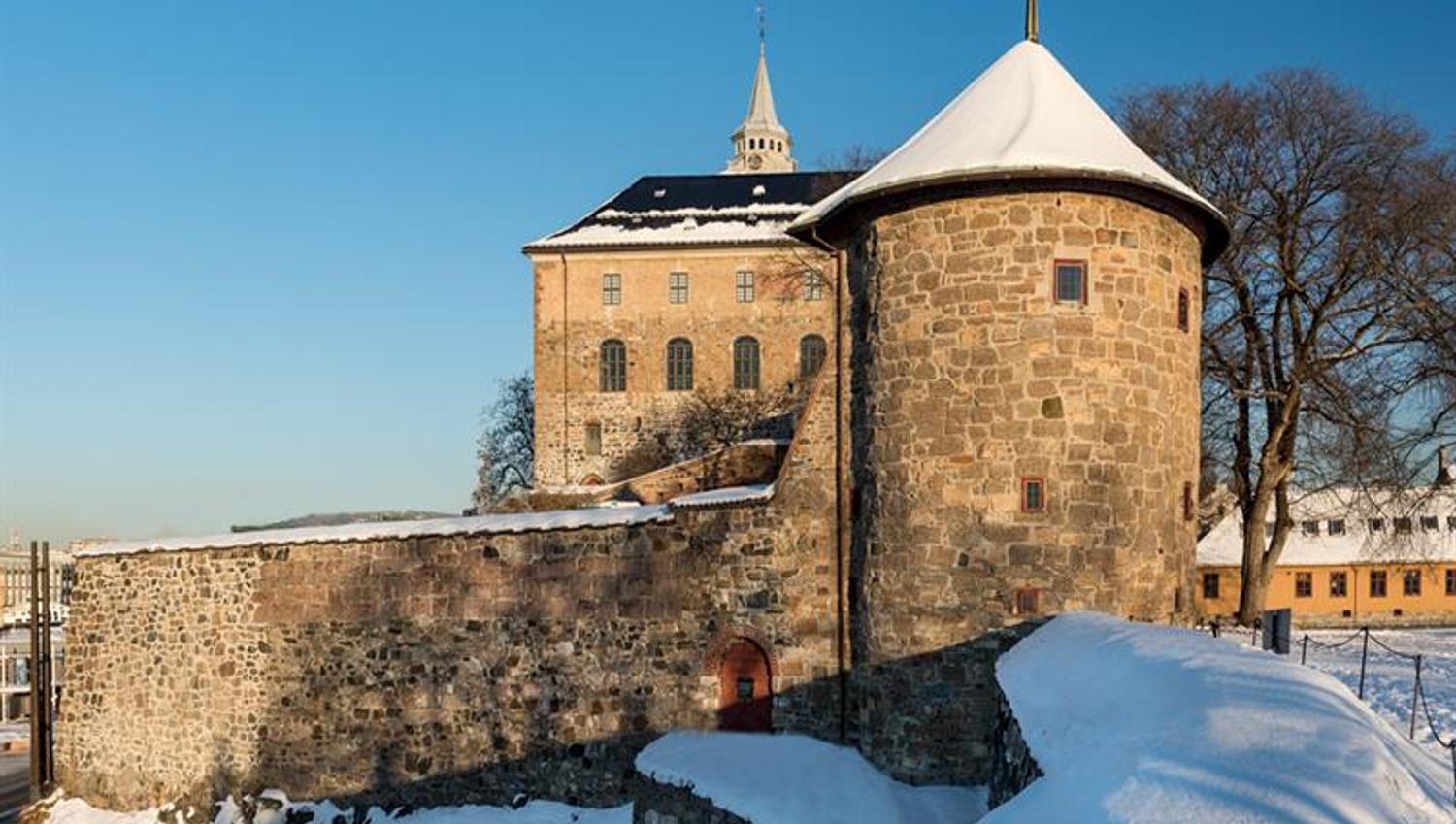 Vinterbilde av Munks tårn med slottet i bakgrunnen. Snø på bakken.