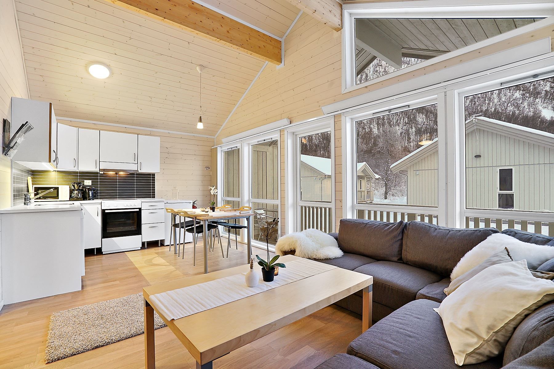 Open-plan living room with kitchen, dining table, and sofa, bright and modern interior