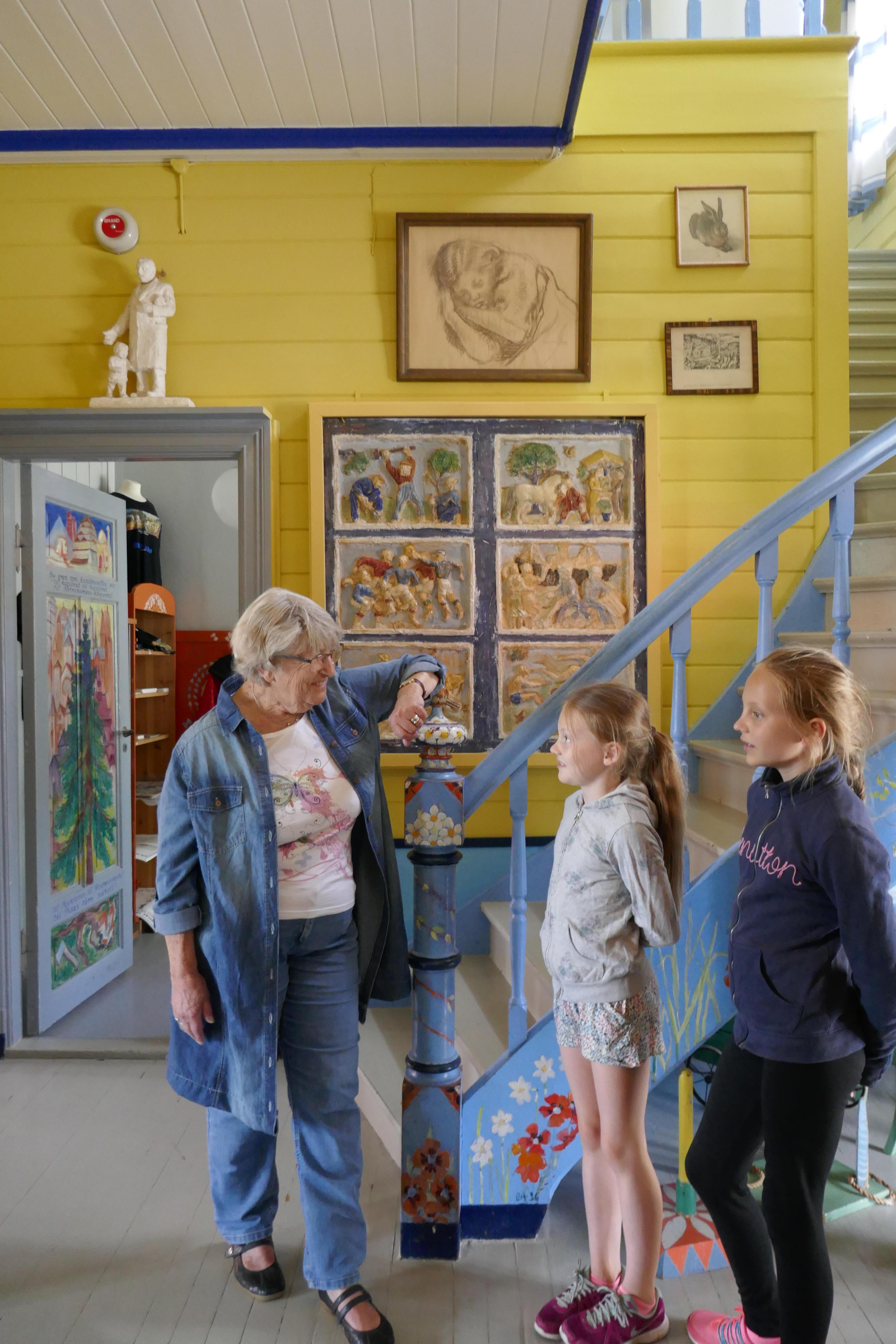 Dame og to jenter i en gul gang