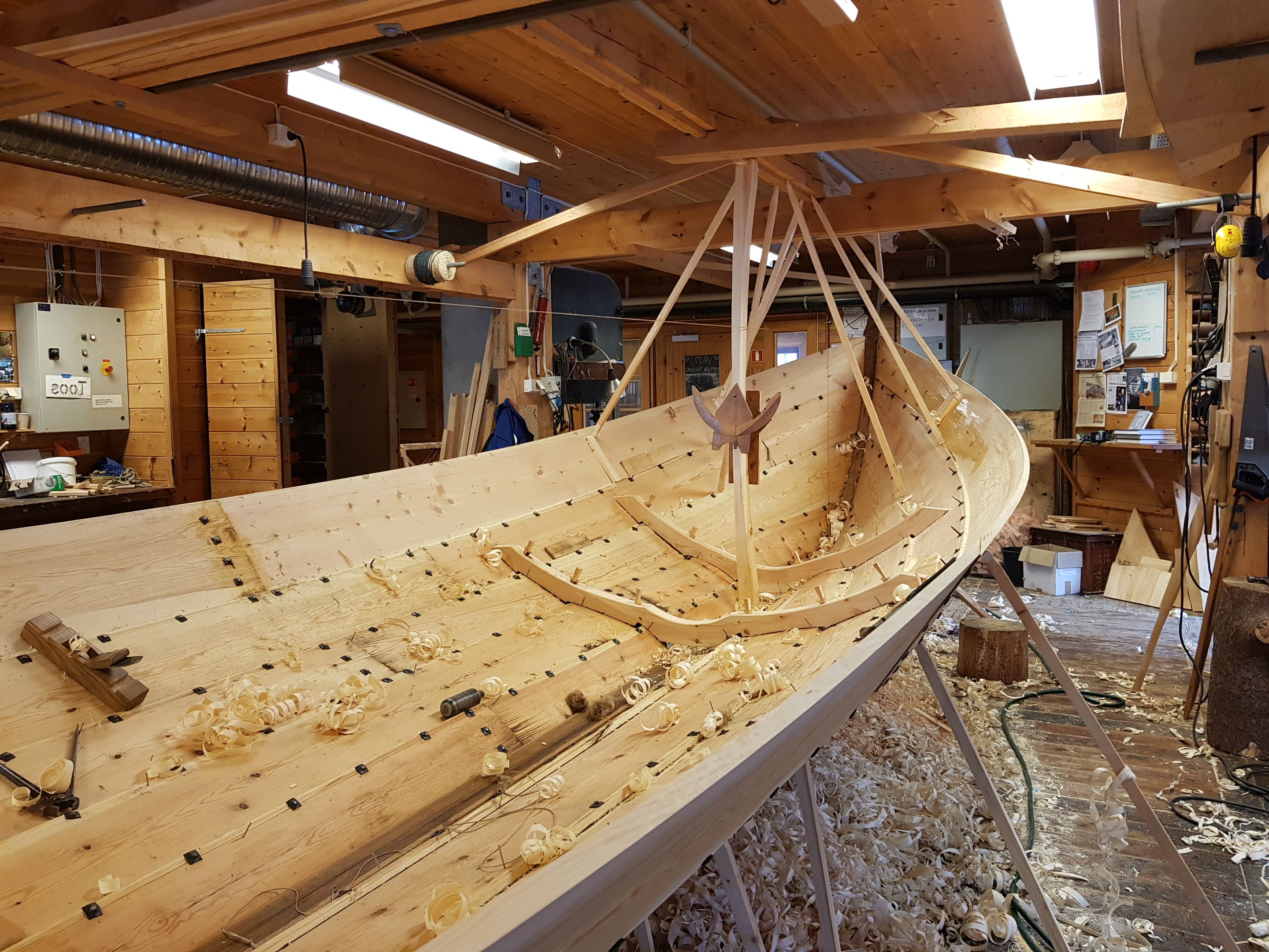 Construction of a new wooden boat at Hardanger Maritime Center with wood shavings on the floor.