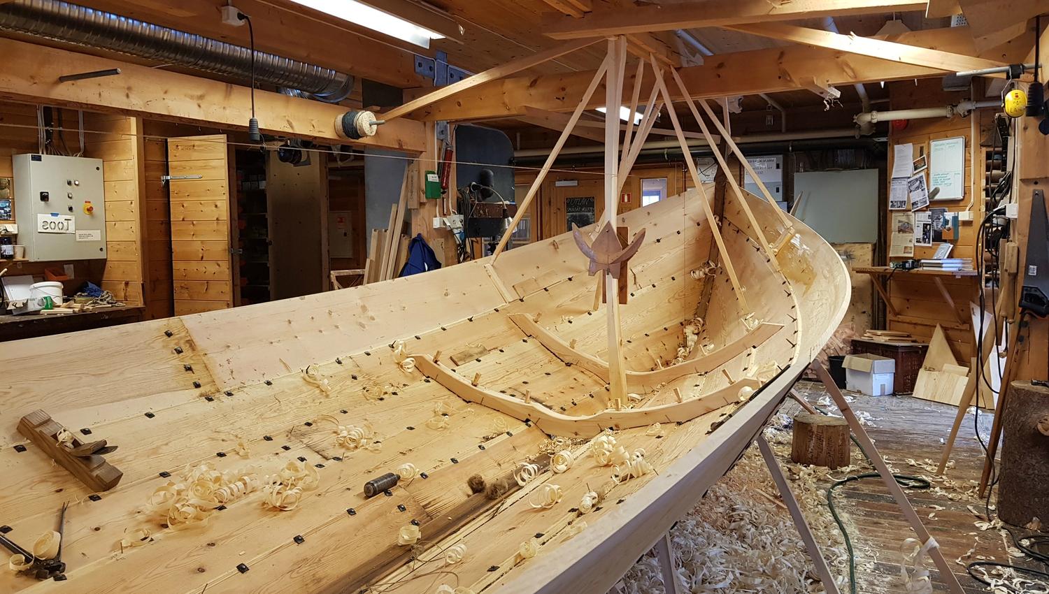 Construction of a new wooden boat at Hardanger Maritime Center with wood shavings on the floor.