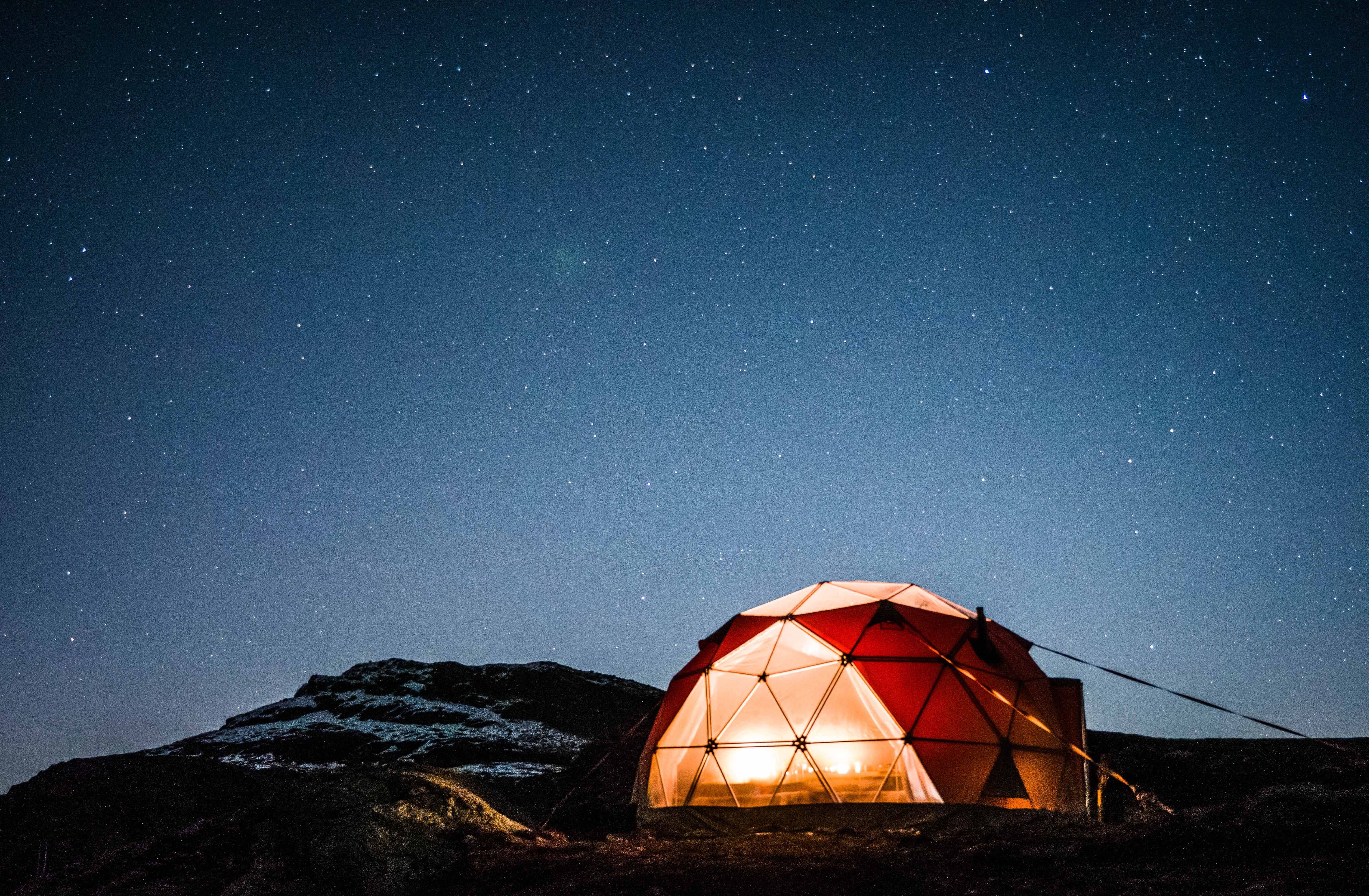 Oppvarma geodome lyser varmt i vinterlandskapet ved Trolltunga under klar nattehimmel.