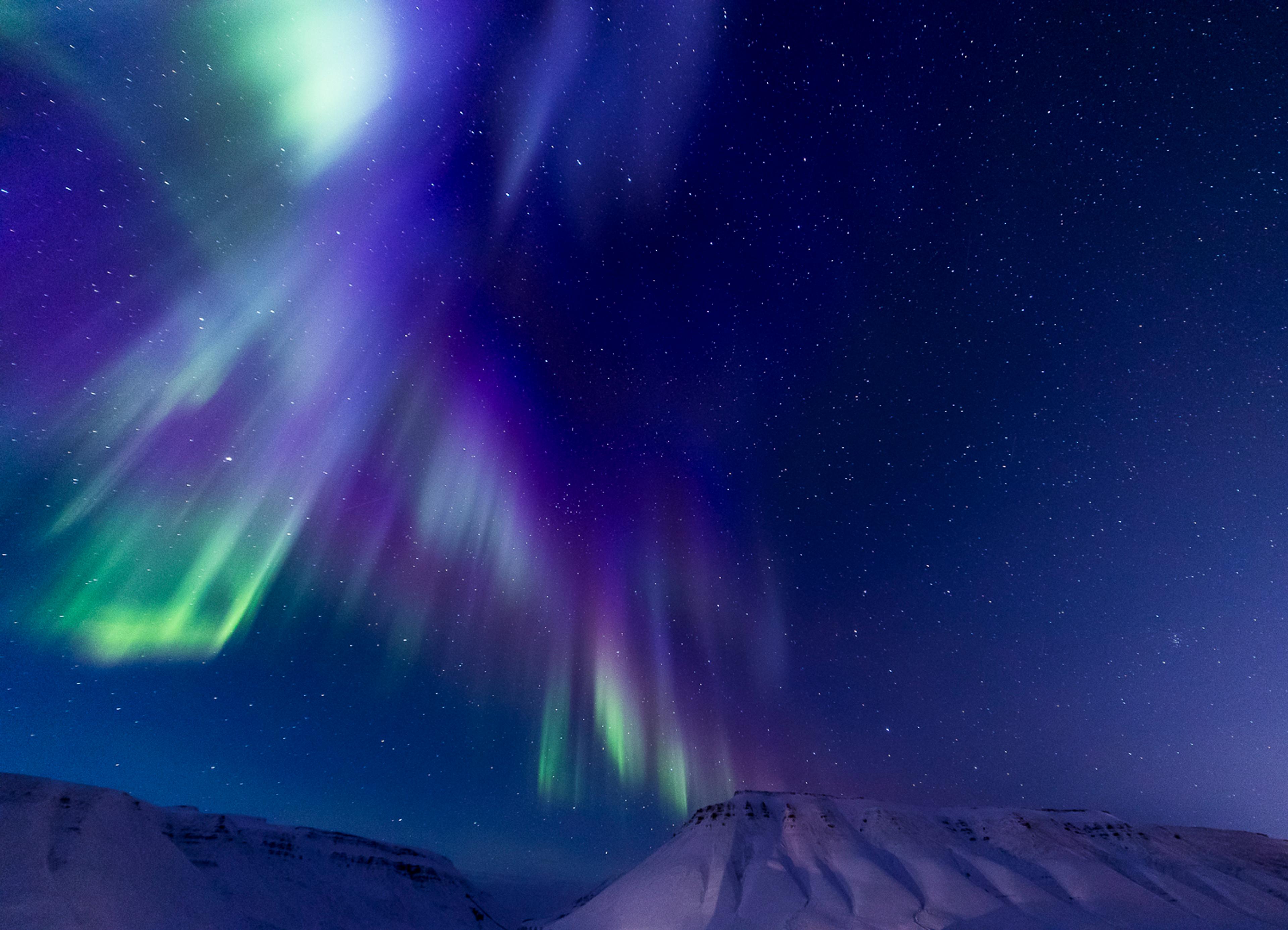 Blue and purple northern lights above the mountains