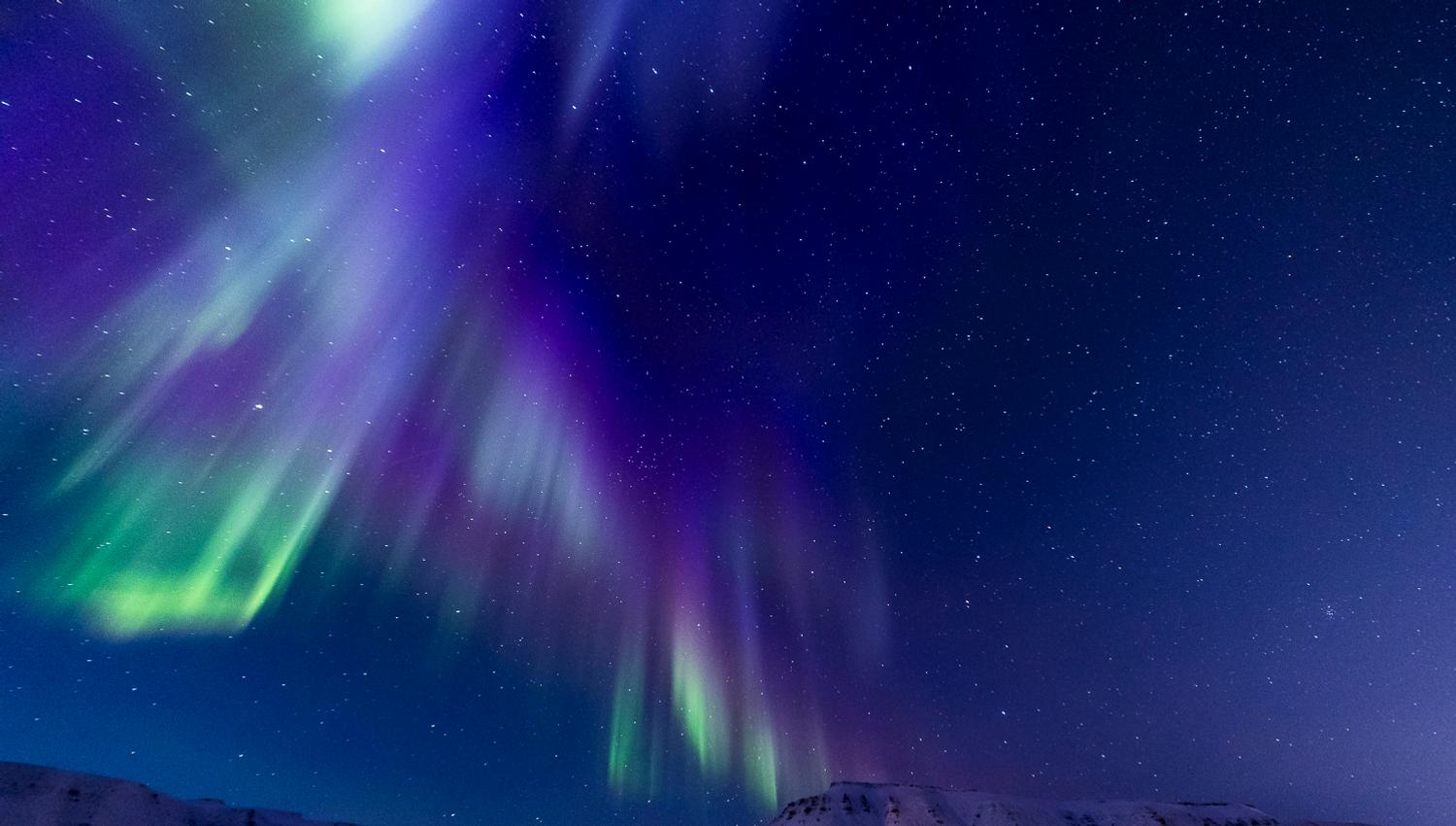 Nordlys som skinner over fjell