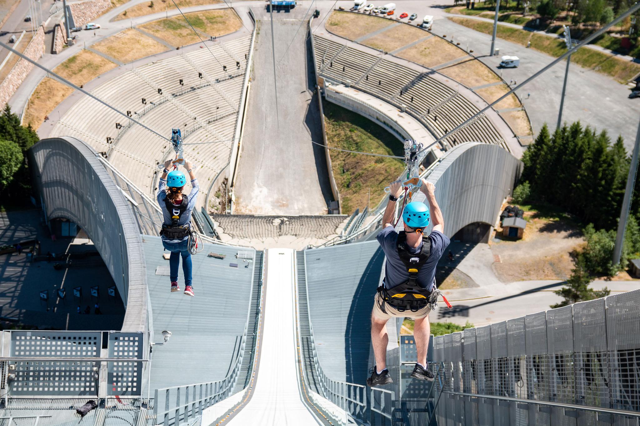 Two people ziplining down Holmenkollen Ski Jump.