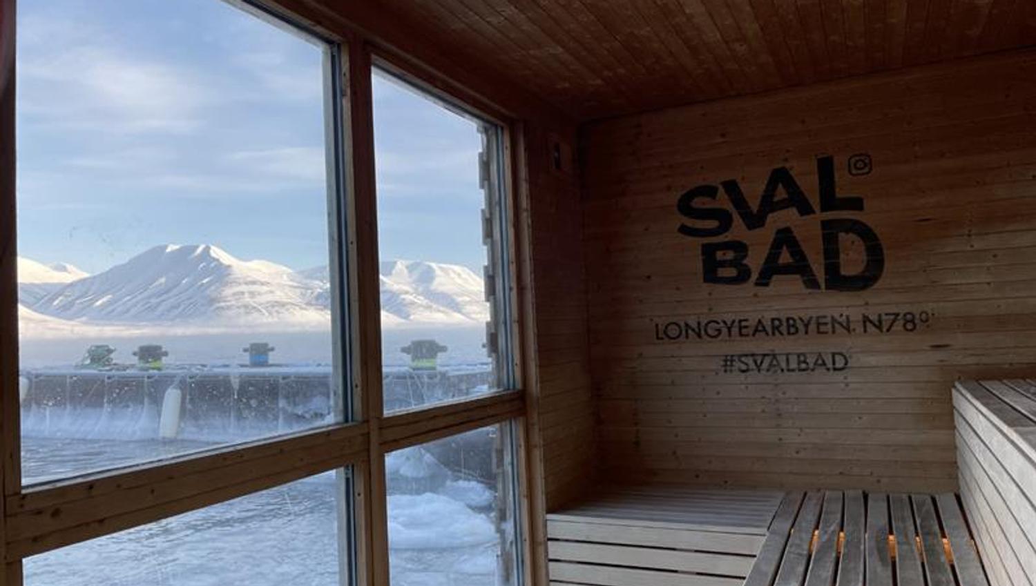 Utsikten mot fjellandskap og en fjord fra innsiden av badstuen