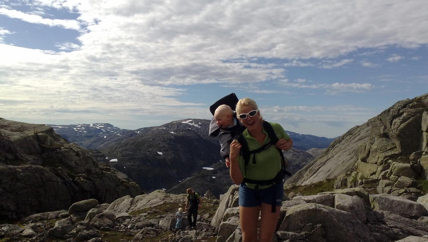 Familie på fjelltur til Røldalssåto under klar himmel, omgitt av storslått natur og vidder.