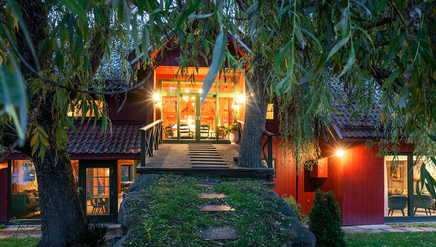 Bro opp til låven, om kvelden, låven lyser opp i mørket.