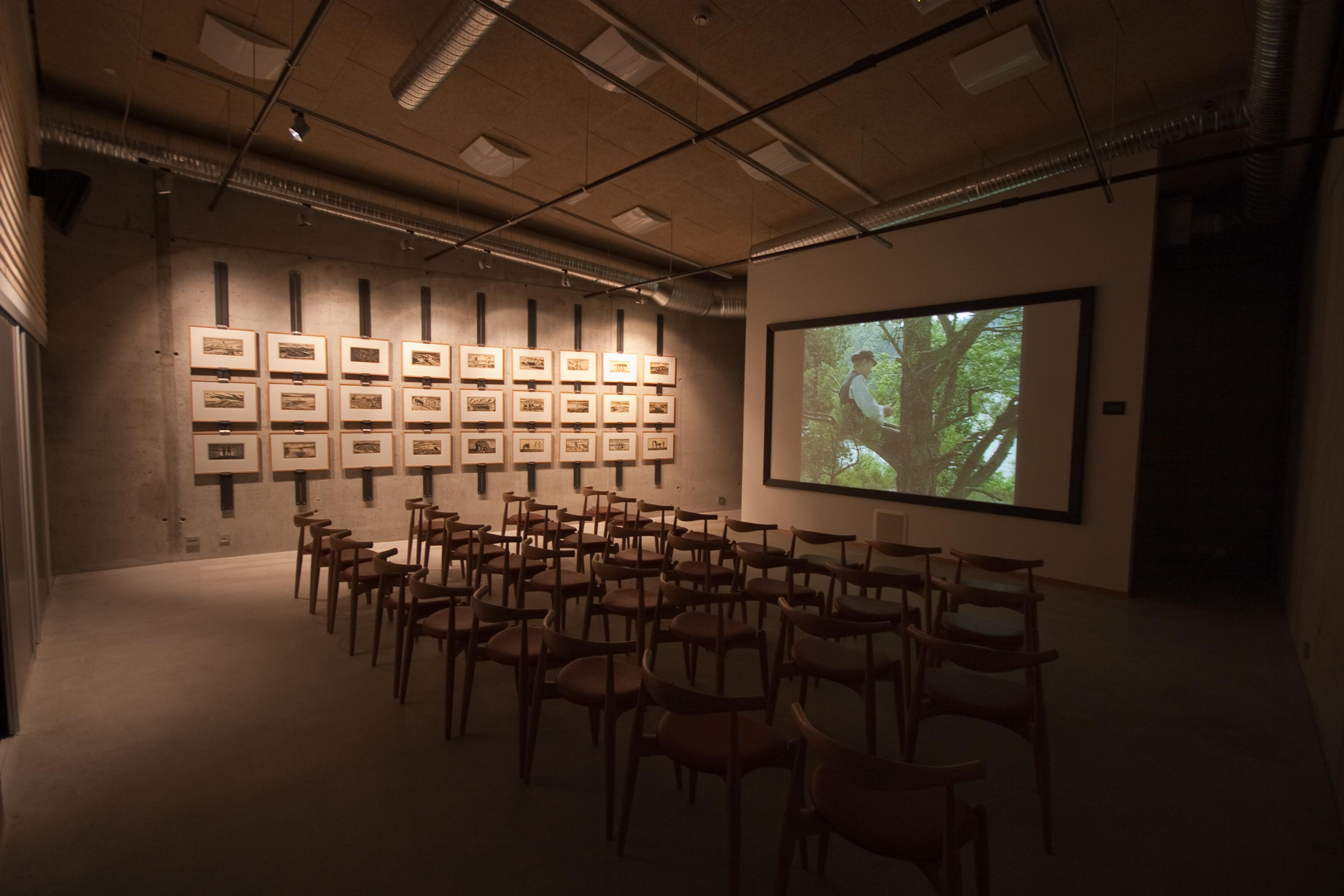 Room with many chairs facing a large screen