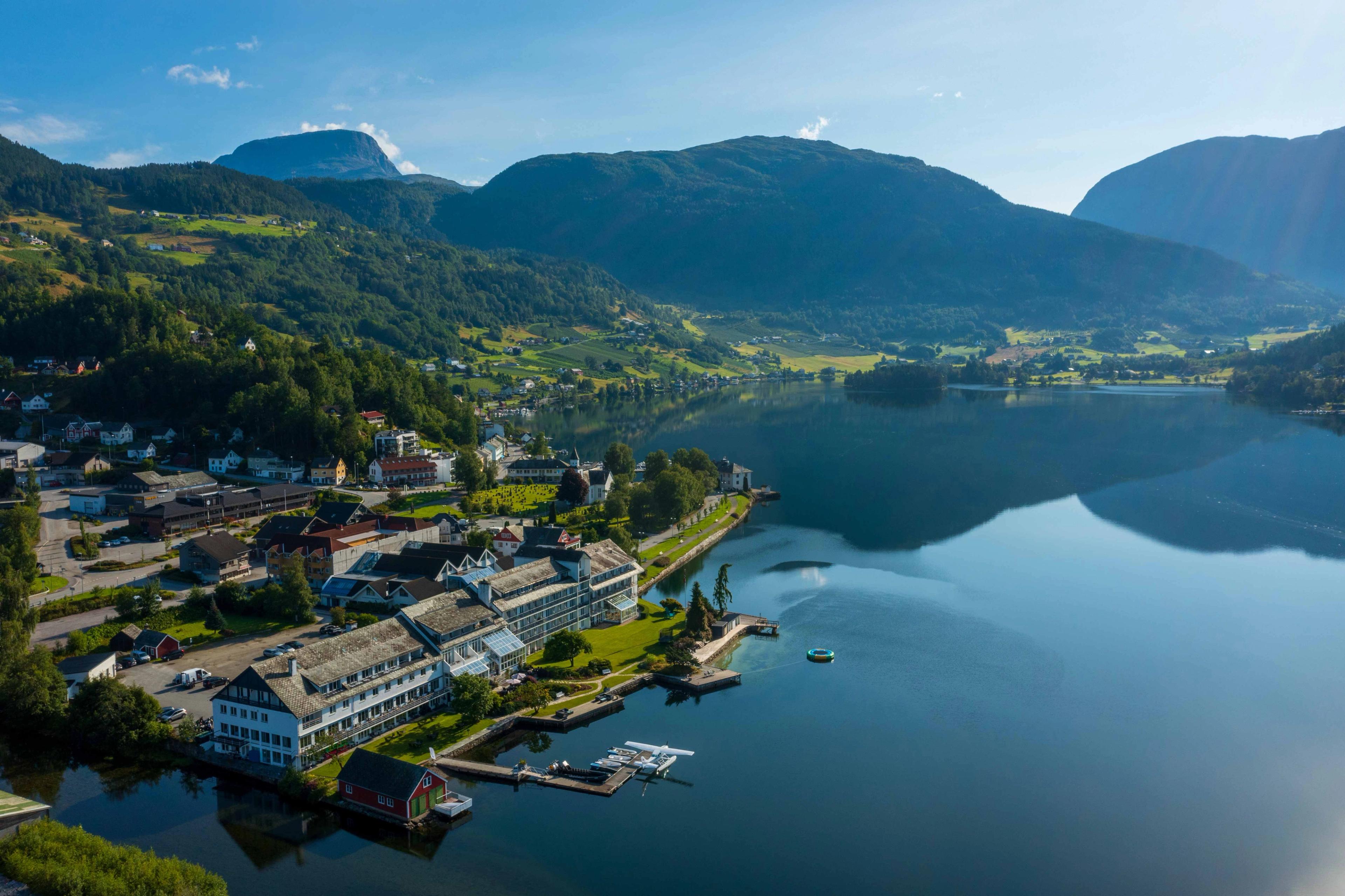 Aerial view of Brakanes Hotel in Hardanger, with stunning surroundings of fjords, mountains, and picturesque landscape.