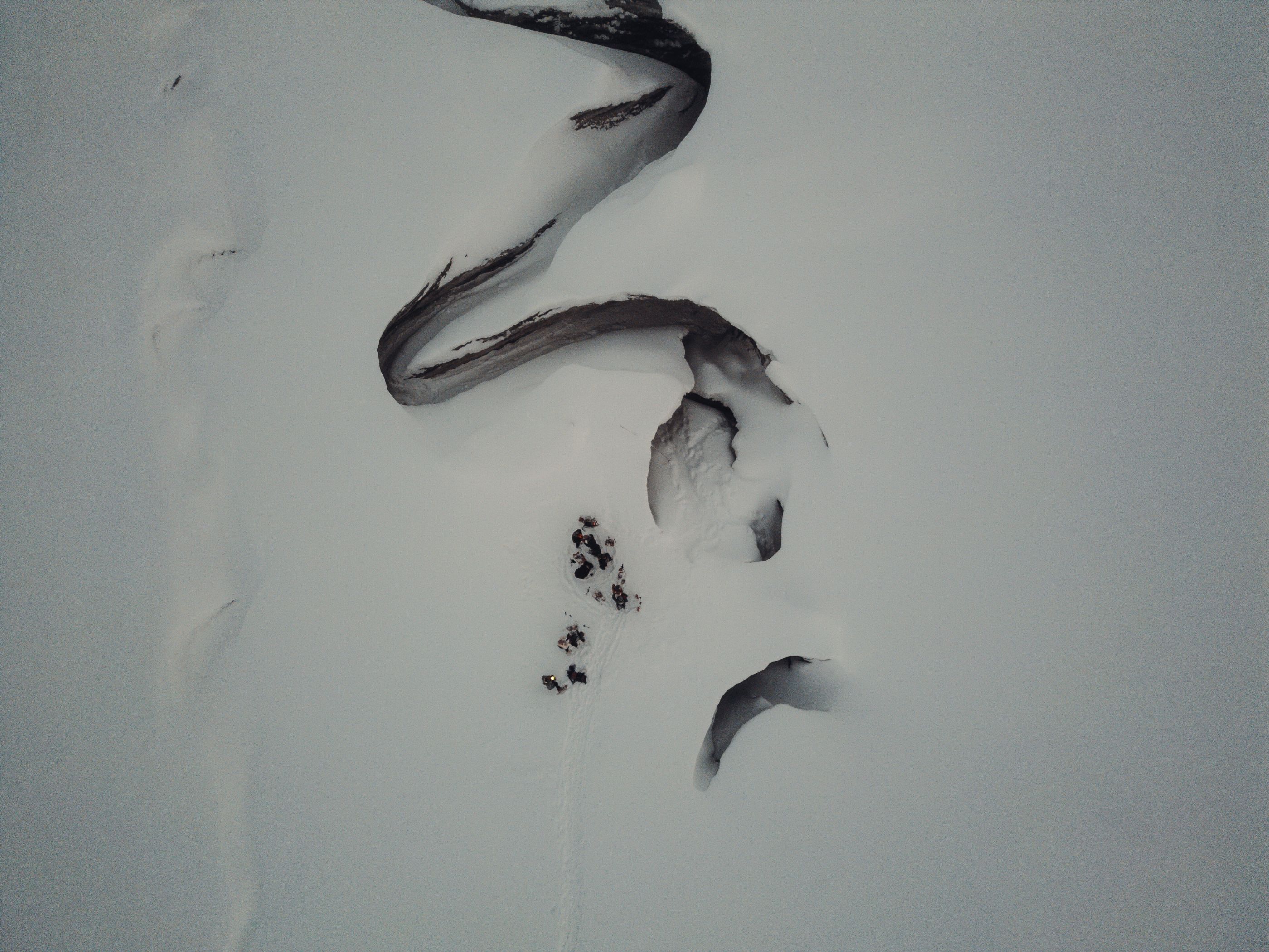 Drone photo of a group of people standing next to a crevasse in a glacier