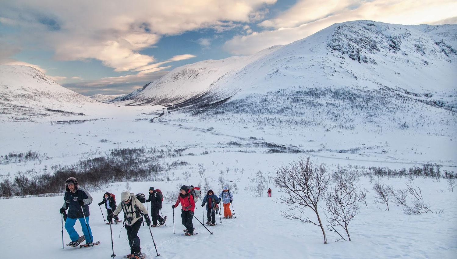 People hiking in snow-covered mountains wearing winter gear.