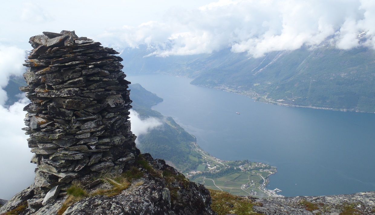A cairn at the top of Dronningstien with a view of the fjord and the village of Lofthus.