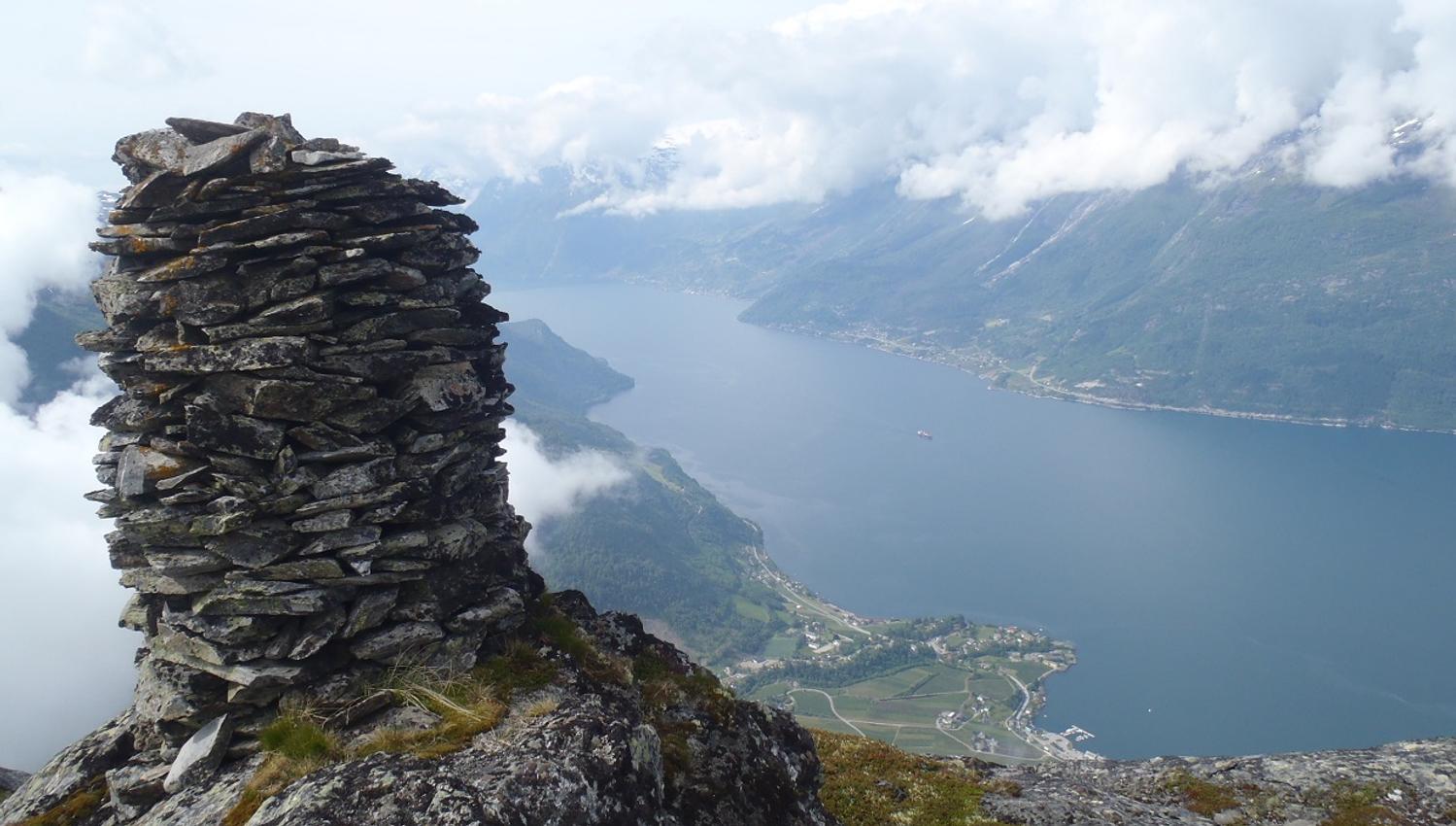 A cairn at the top of Dronningstien with a view of the fjord and the village of Lofthus.