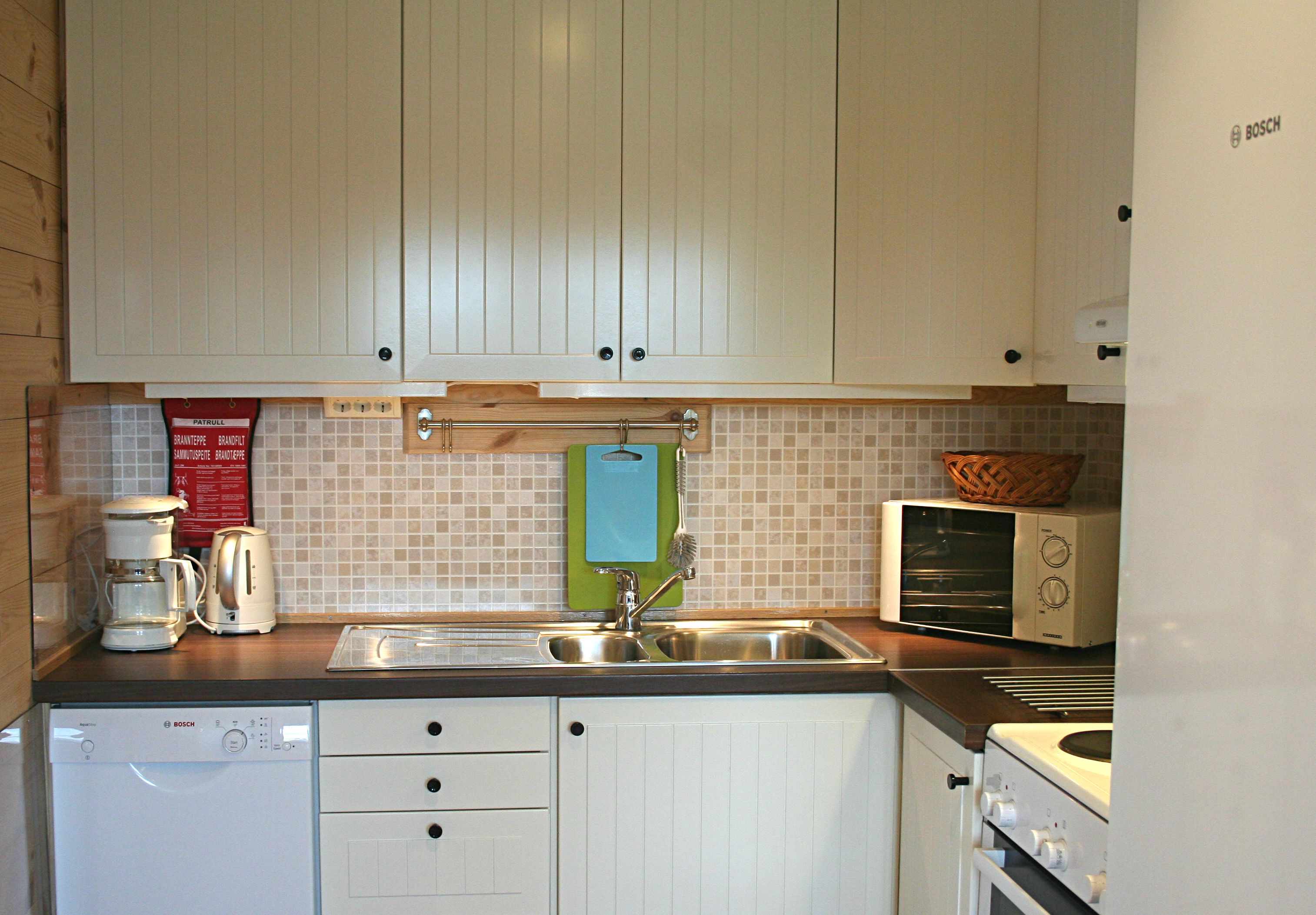 Fullt utstyrt kjøkken med kvite skap, komfyr og oppvaskmaskin ved Vågen Rom og Hytteutleige i Hardanger.