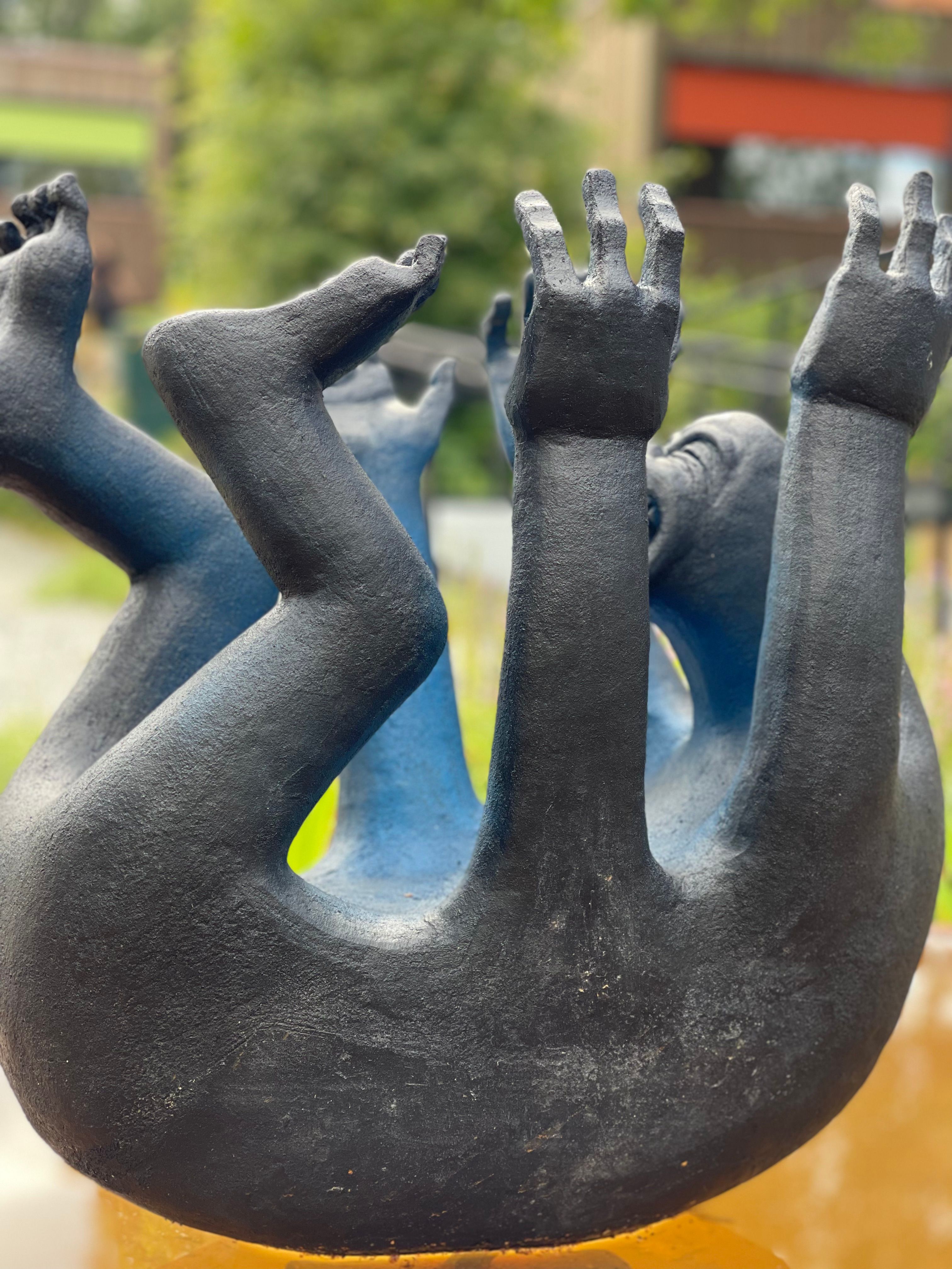 svart skulptur som ser ut som en lite menneske med mange armer og ben